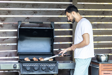Man cooking meat on barbecue grill. Close-up of delicious meal 