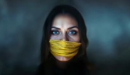 portrait d'une femme, vu de face, avec un bâillon jaune devant la bouche 