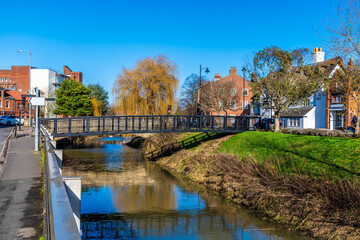 A view towards a footbridge over the River Welland opposite Welland Place in the centre of Spalding, Lincolnshire on a bright sunny day - obrazy, fototapety, plakaty