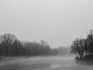 Fog rising from a partially iced over lake on a cold winter day