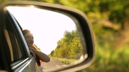 Smiling travel woman looking at window car road trip enjoy summer trees sun light back mirror reflection view. Happy female tourist admiring scenery freedom explore lifestyle adventure auto driving - obrazy, fototapety, plakaty