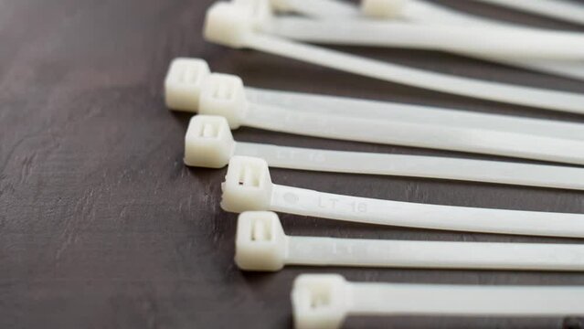 Pile of unused nylon cable ties on a wooden background close up. Industrial tool concept