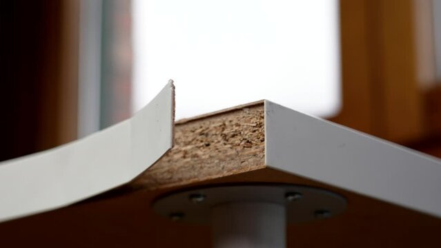 Damaged defective white table in a room with a peeling surface close up