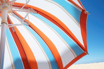 An orange and white striped umbrella on the beach. Perfect for summer vacation and beach-themed designs
