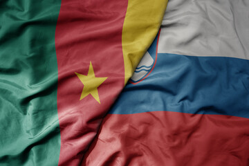 big waving national colorful flag of slovenia and national flag of cameroon .