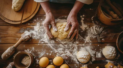 Fotobehang A bakers hands kneading dough on a flour-dusted wooden surface surrounded by fresh pastries and baking tools. © Leo