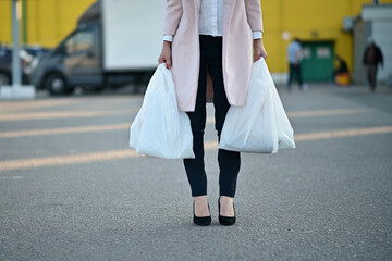 A woman holds bags of groceries on the road near a supermarket. Close-up