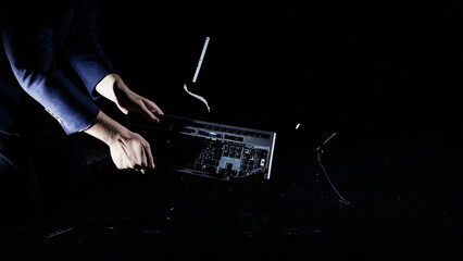 Man banging and hitting computer keyboard on a hard floor, isolated on a black background, slow...