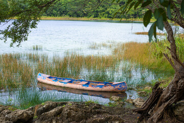weathered canoe on the shore of a fresh water lake in the Central American jungle