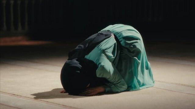 Young Muslim Woman Prostrating in Prayer in a Mosque at Night. The Act of Sujud