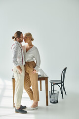 appealing couple in chic attires posing lovingly and preparing to kiss while at office, work affair