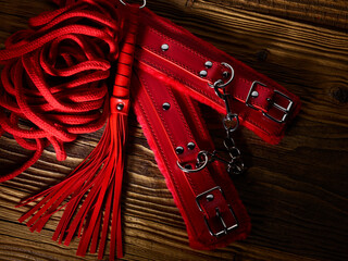 BDSM sex toys set in a red color over aged wooden planks backdrop - obrazy, fototapety, plakaty