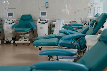 Comfortable armchairs for blood donors arranged in row in empty medical center