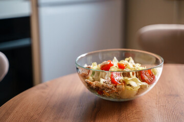 Dining table with vegetable diet salad with chicken in a glass bowl in a modern kitchen