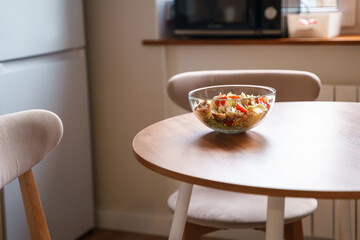 Dining table with vegetable diet salad with chicken in a glass bowl in a modern kitchen
