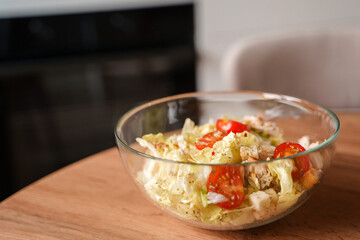 Dining table with vegetable diet salad with chicken in a glass bowl in a modern kitchen