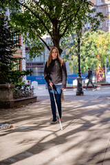 Blind woman with white cane walking on the street at the city