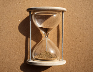 hourglass with a brown sand inside, sitting on a brown surface