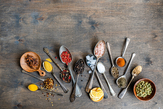 Assorted spices and seeds in spoons on rustic wood