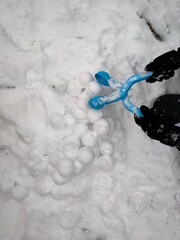 Child making snowballs with a plastic snowball maker