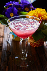 cosmopolitan cocktail garnished with ice on wooden table