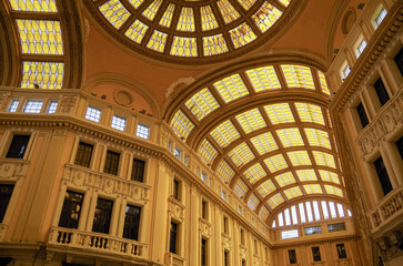 Run down opulent interior architecture with glass dome and roof, statues, balconies and closed shops and boutiques