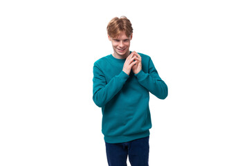 portrait of a positive bright young european man with red hair in a blue sweater on a white background