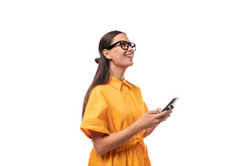 a young well-groomed woman with black straight hair dressed in a yellow dress chats on a smartphone