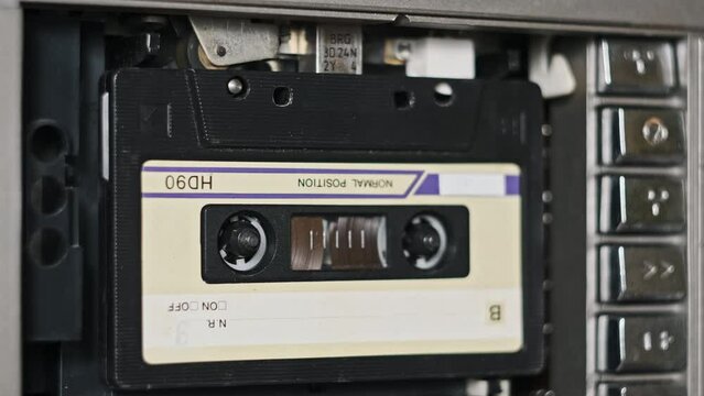 Audio cassettes changing in a retro tape player. Many different color audio cassettes play in a tape deck. Vintage tape reels rotate in the recorder. Calls, rec, archive, music 80s, 90s, nostalgic