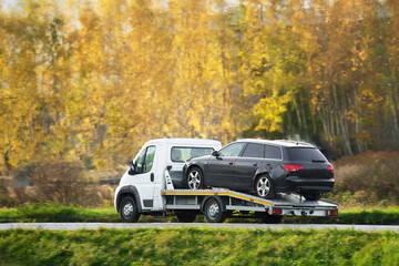 Emergency roadside assistance in action as a tow truck carries a broken down SUV on the highway.