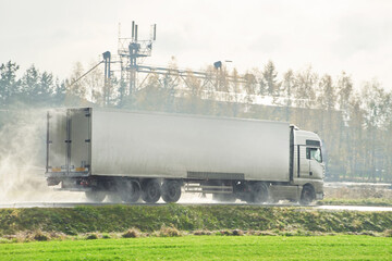 Front-side view of a white truck on the highway during heavy rain. Delivering goods in bad conditions.