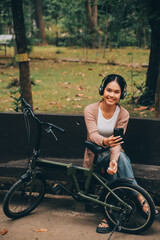 Obraz premium Happy young Asian woman while riding a bicycle in a city park. She smiled using the bicycle of transportation. Environmentally friendly concept.