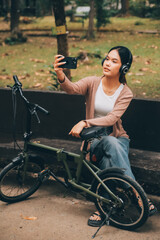 Obraz premium Happy young Asian woman while riding a bicycle in a city park. She smiled using the bicycle of transportation. Environmentally friendly concept.