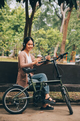 Obraz premium Happy young Asian woman while riding a bicycle in a city park. She smiled using the bicycle of transportation. Environmentally friendly concept.