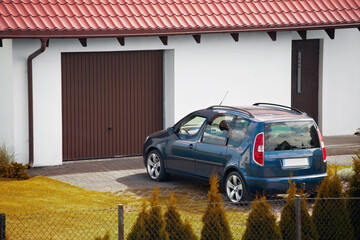 A family car parked against the backdrop of a well-kept home with white walls and a brown garage...