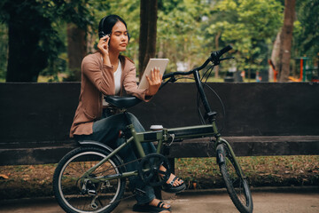 Obraz premium Happy young Asian woman while riding a bicycle in a city park. She smiled using the bicycle of transportation. Environmentally friendly concept.