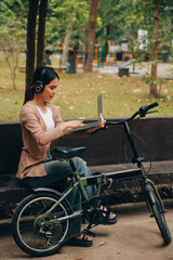 Happy young Asian woman while riding a bicycle in a city park. She smiled using the bicycle of transportation. Environmentally friendly concept.