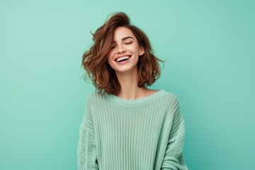 A beautiful young smiling girl on a coloured background has her hands up in the air and is laughing