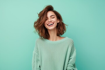 Fototapeta premium A beautiful young smiling girl on a coloured background has her hands up in the air and is laughing