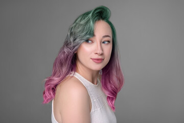 Naklejka premium Trendy hairstyle. Young woman with colorful dyed hair on grey background