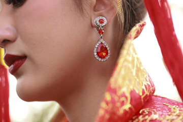 beauty, jewelry,  dressing  accessories, people, and luxury concept - close up of beautiful asian woman  with red shiny  beautiful earring