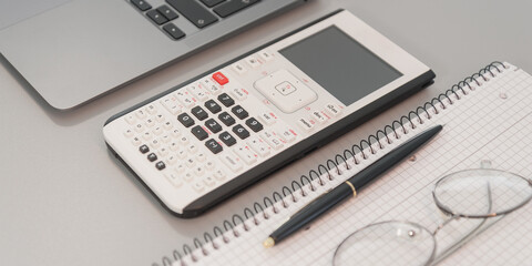 calculator laptop and glasses on a gray background