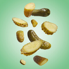 Tasty pickled cucumbers falling on green background