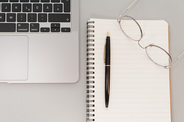 laptop and glasses with notepad on gray background
