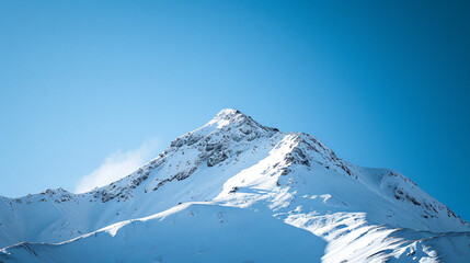 Fototapeta na wymiar A snowy mountain peak under a clear blue sky.