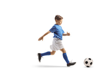 Boy in a blue and white football kit running fast with and leading a ball