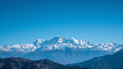 A majestic mountain range with snow-capped peaks under a clear blue sky.