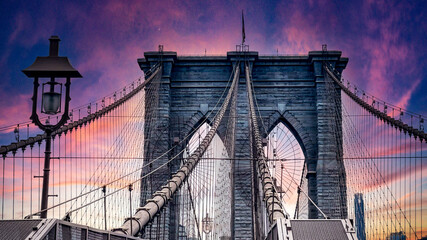 Obraz premium Walking across the famous, incredible and wonderful Brooklyn Bridge that connects the boroughs of Manhattan and Brooklyn in New York City (USA) an incredible sunset.