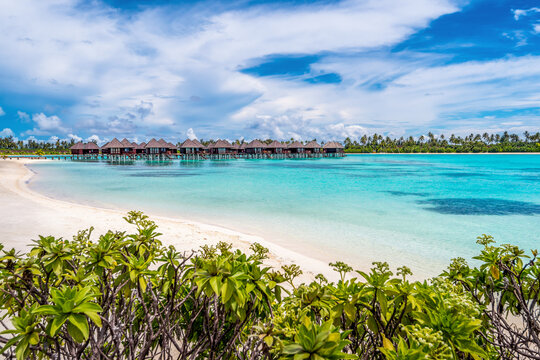 Scenic view of white sand beach in Maldives with turquoise pristine water and dramatic sky
