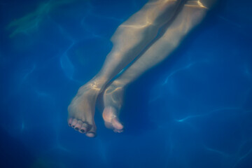 The legs of a young woman in a swimming pool